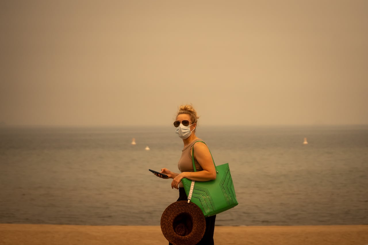People are pictured during a period of heavy wildfire smoke from the nearby Bald Range fire near Okanagan Lake in Penticton, British Columbia, on Sunday Aug. 9, 2026.