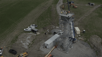 An aerial view of construction workers on top of a concrete tower