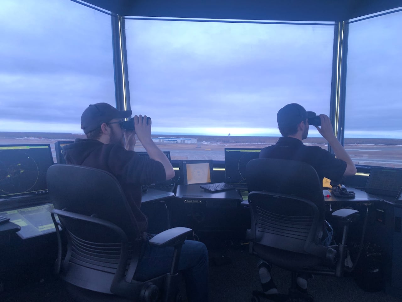 Air traffic controllers watch the distance with binoculars