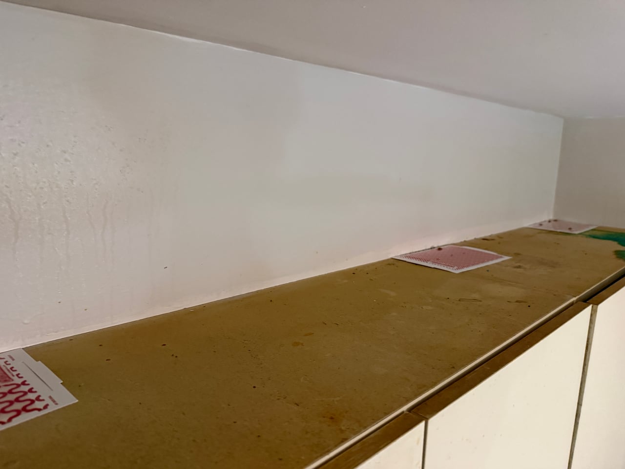 The top of a kitchen cabinet with a yellow stain from grease. There are also some insect traps on it.
