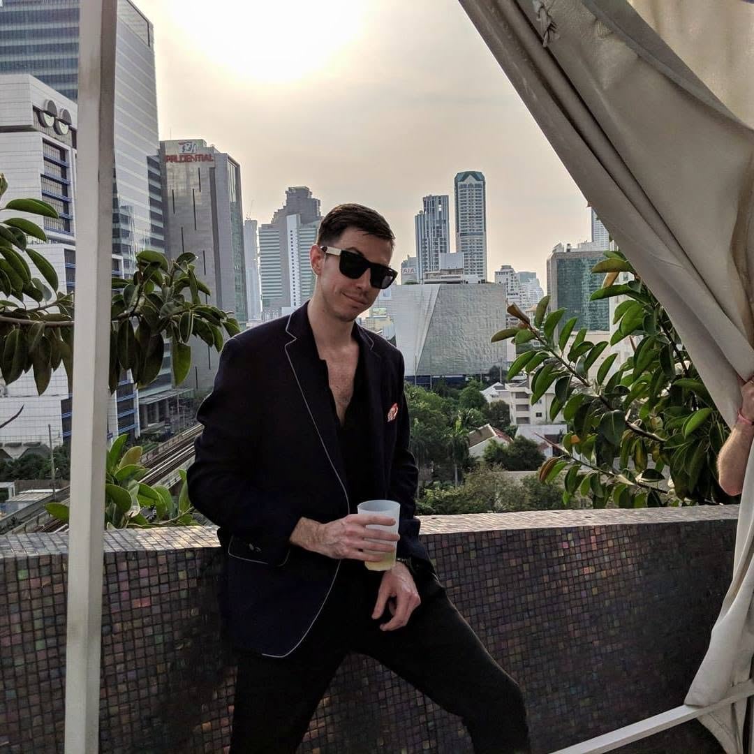 A man holds a plastic cup in front of a city backdrop