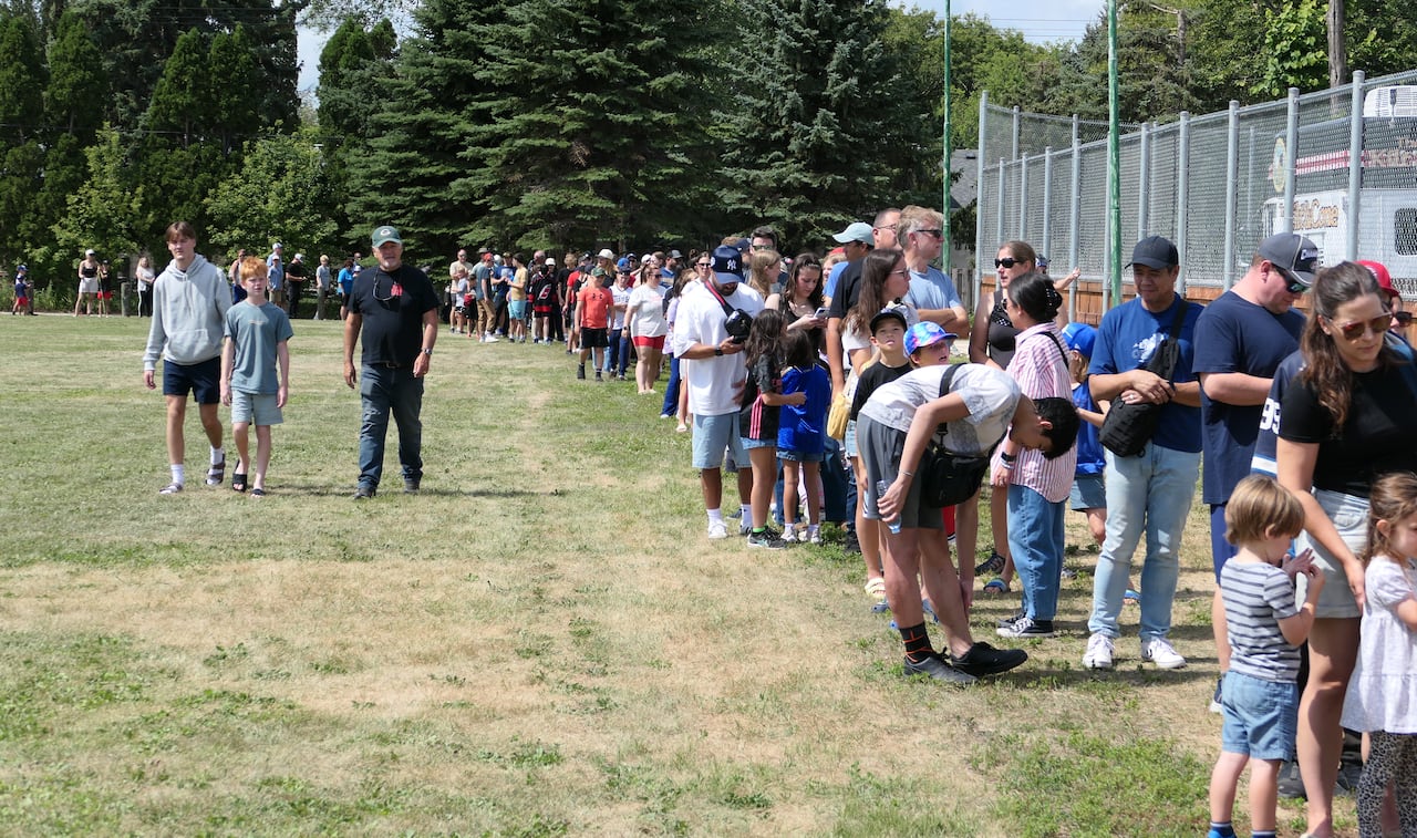 A lineup of people waiting outdoors.