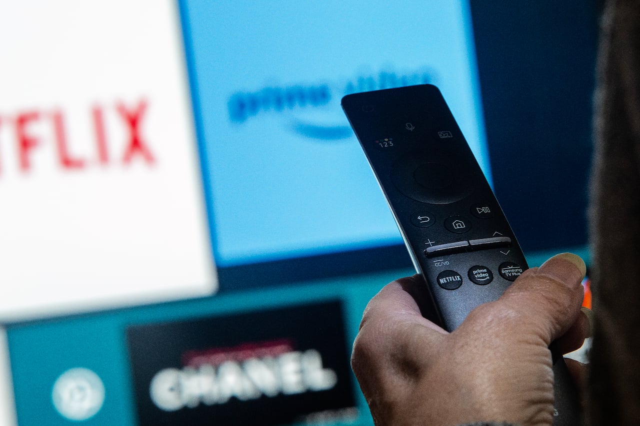 A man holds a remote in front of a TV in an illustration.