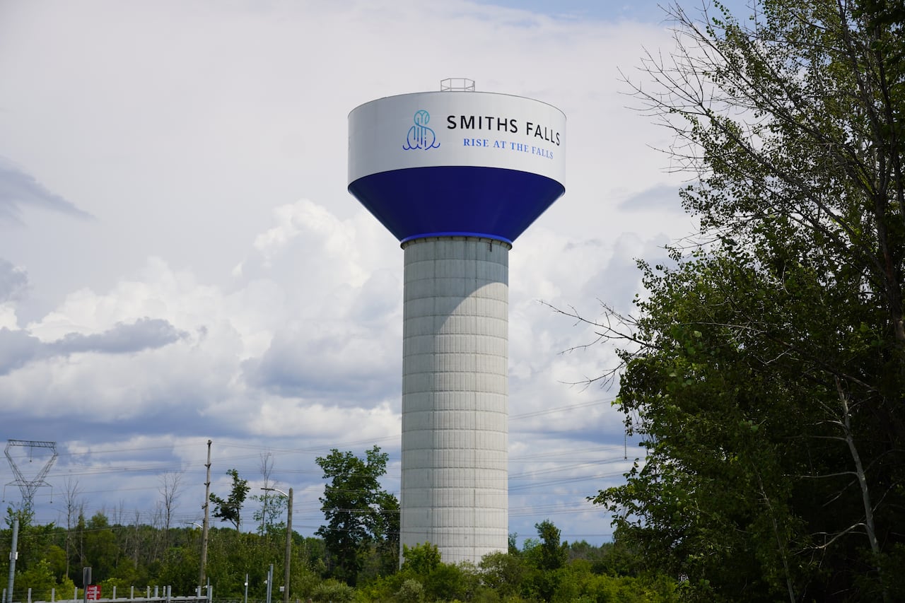 A white water tower with a blue town logo on it.