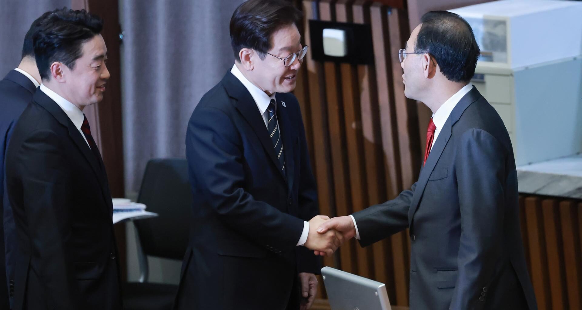 President Lee Jae Myung, center, shakes hands with Rep. Joo Ho-young, then deputy speaker of the National Assembly, after giving a speech on the government