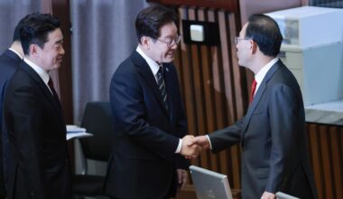 President Lee Jae Myung, center, shakes hands with Rep. Joo Ho-young, then deputy speaker of the National Assembly, after giving a speech on the government