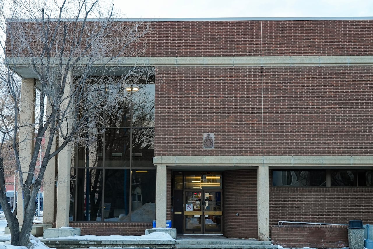 A red brick building with large glass windows with snow outside.