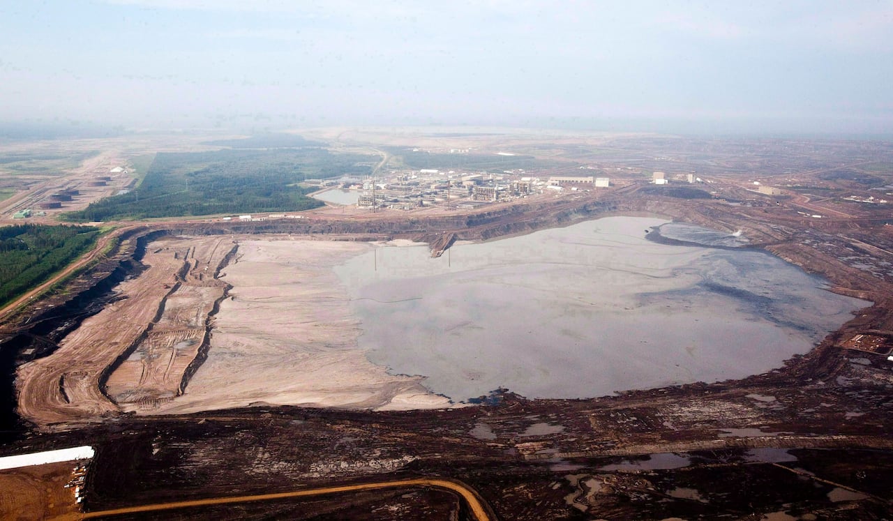A tailings pond next to a mine and a forest.