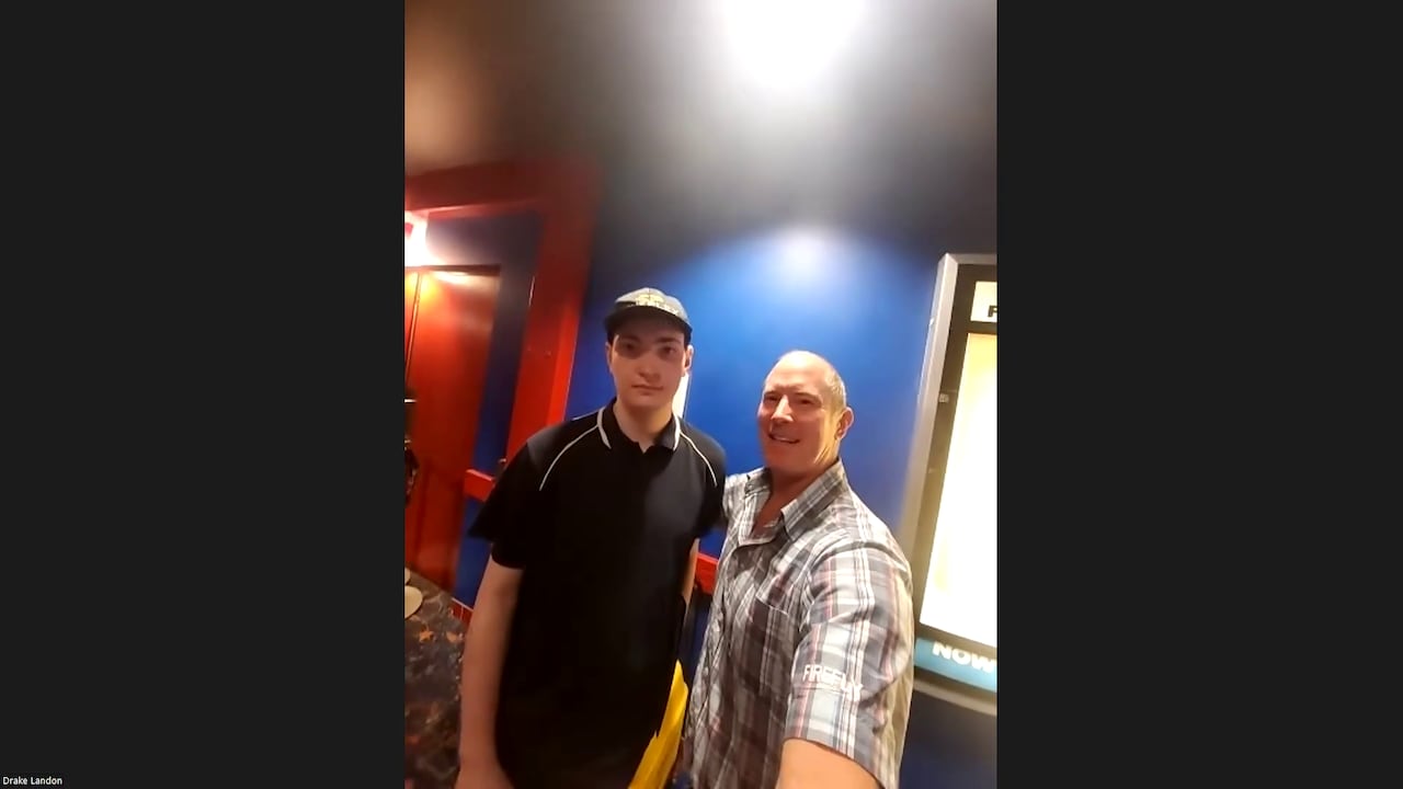 A man stands beside a young theatre employee in uniform.