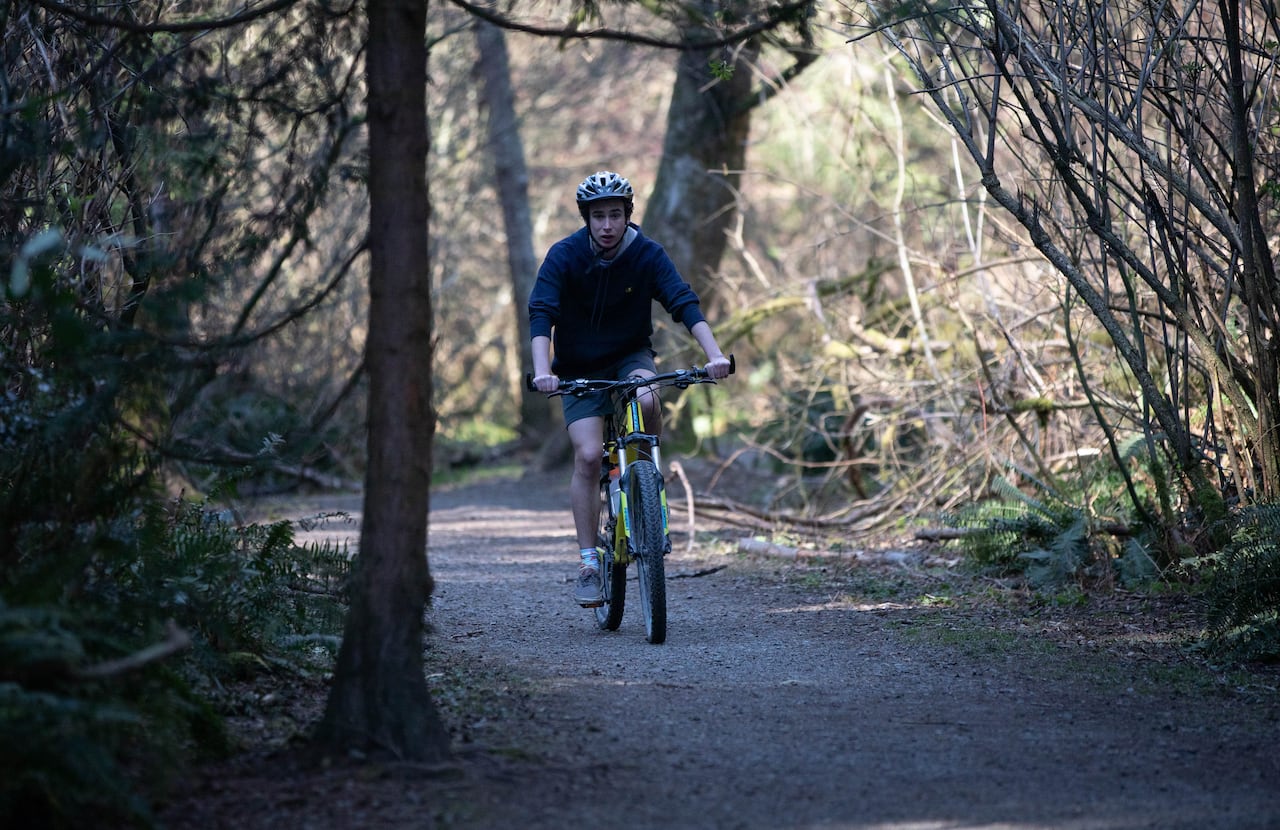 A cyclist is seen on a forested trail.