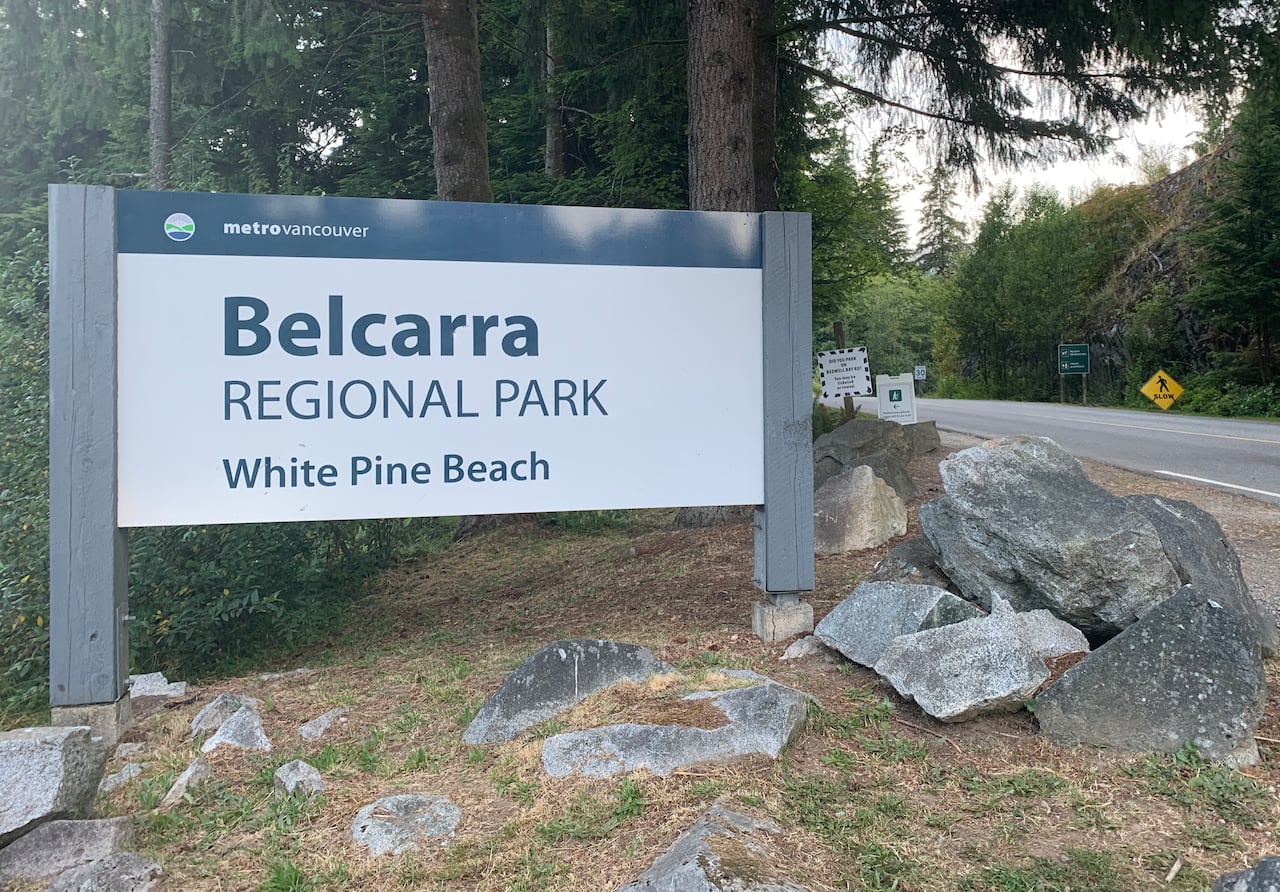 A sign says 'Belcarra Regional Park White Pine Beach' at a forested area.