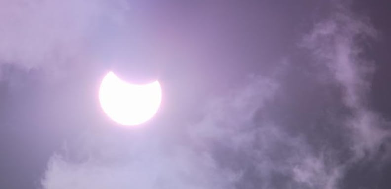 Photo of a partial solar eclipse with the moon cover a small fraction of the sun.