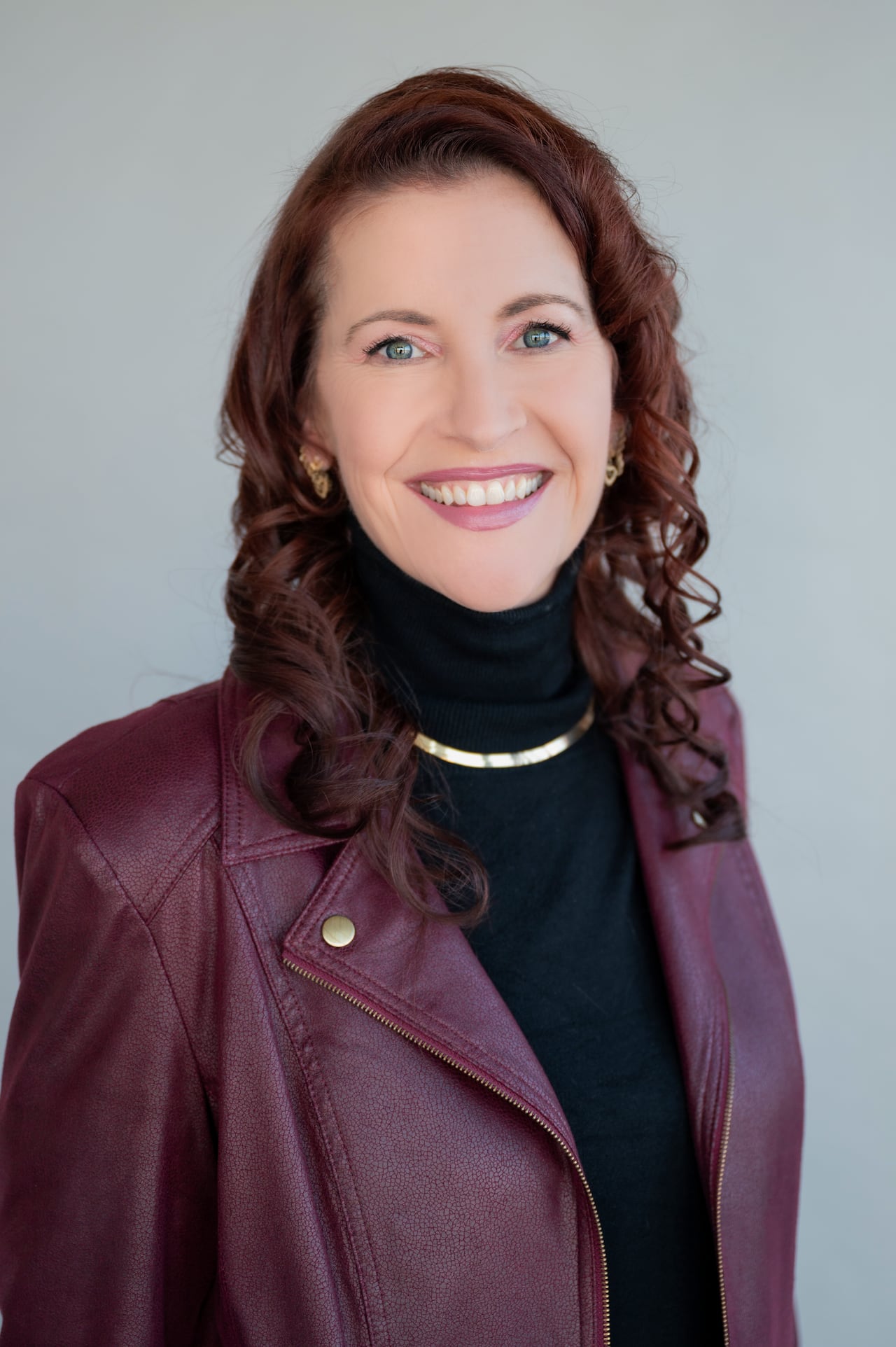 Woman wearing leather jacket and turtle neck in front of grey background