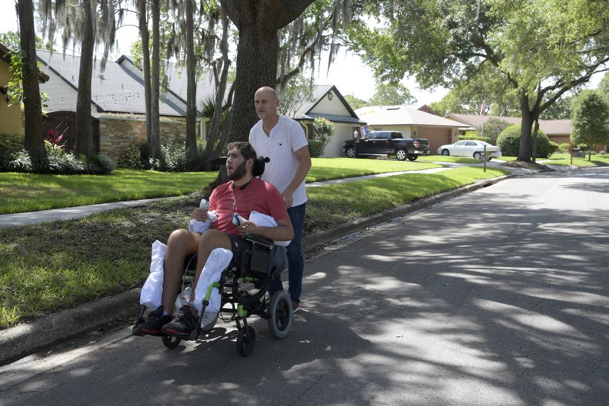 Former professional boxer Prichard Colón is pushed in a wheelchair by his father, Richard Colón, in Winter Park, Florida, on May 22, 2017.