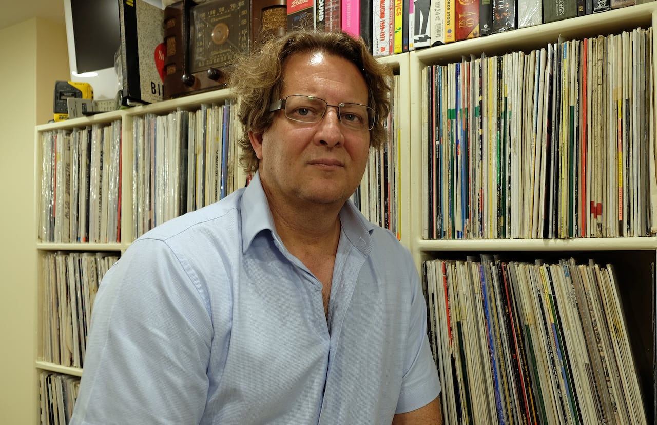 A man stands in front of shelves of vinyl record albums.