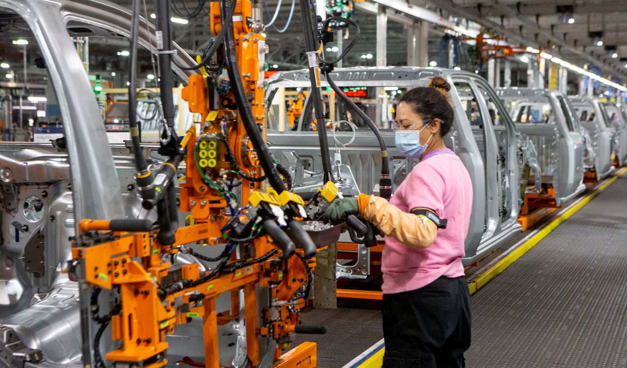 A female autoworker is shown on an assembly line at a car plant.
