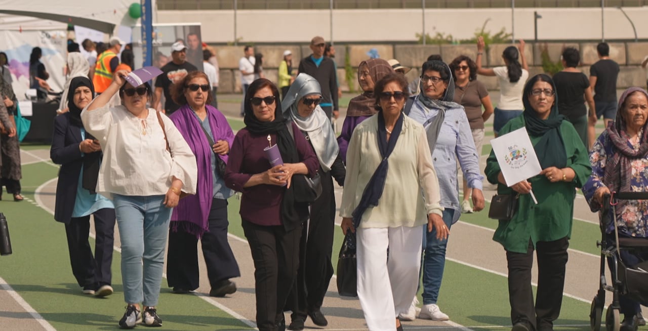 A group of women march on a running track in a group.