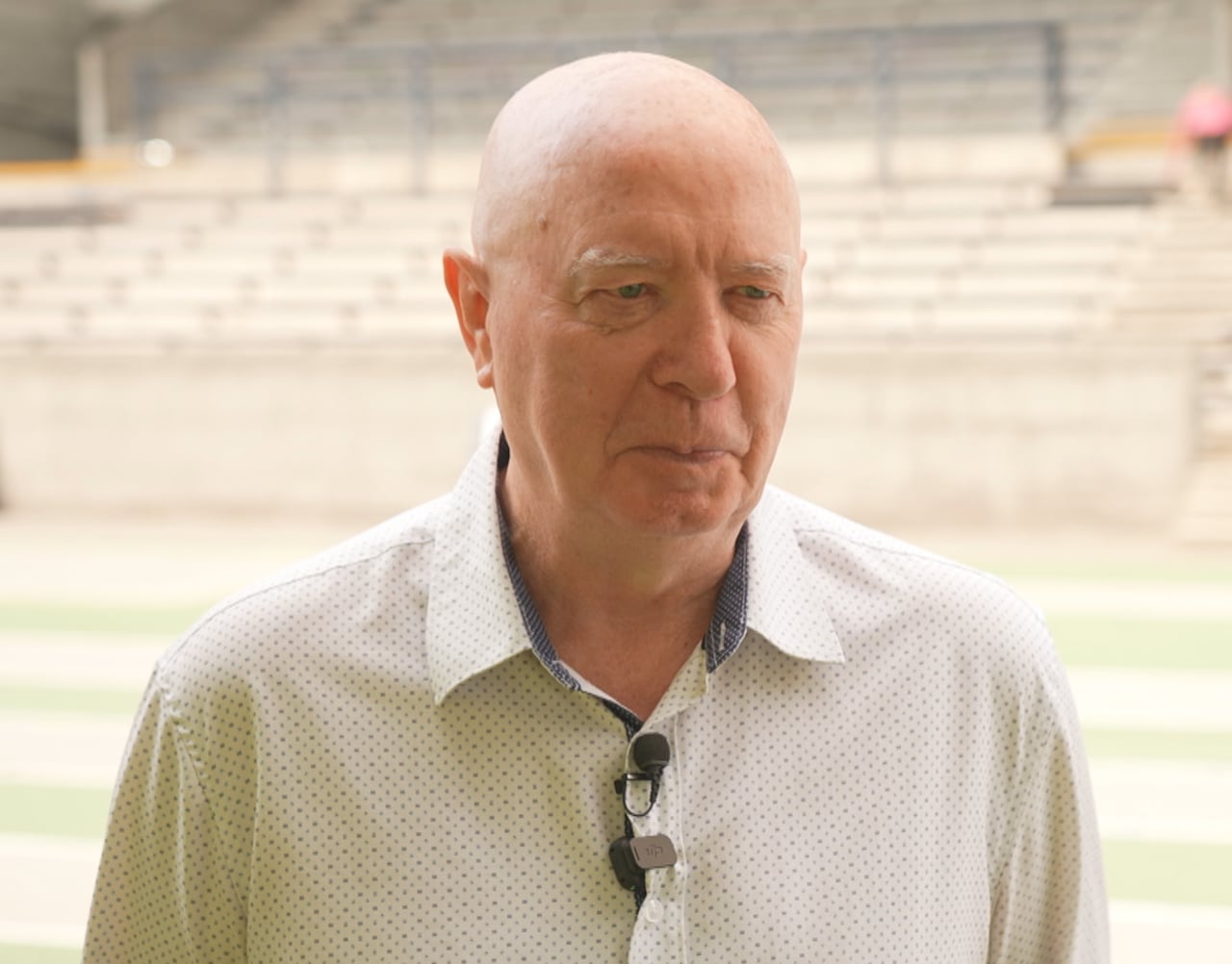 A bald man speaks on a running track.
