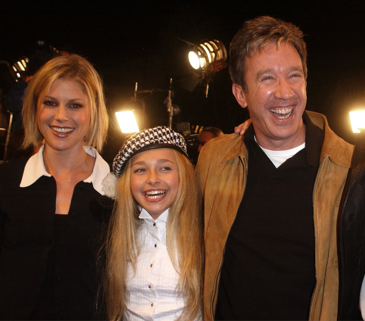 A woman, a young girl and a man all smile while posing for a photo together.