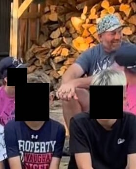 Screenshot from a video that shows a man in a baseball cap sitting next to children. The children's faces are censored.
