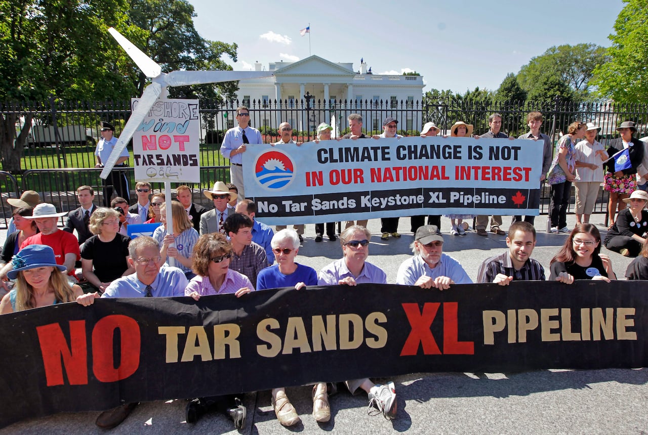 Protesters hold signs in front of the White House including one that reads, 'No tar sands XL pipeline.'