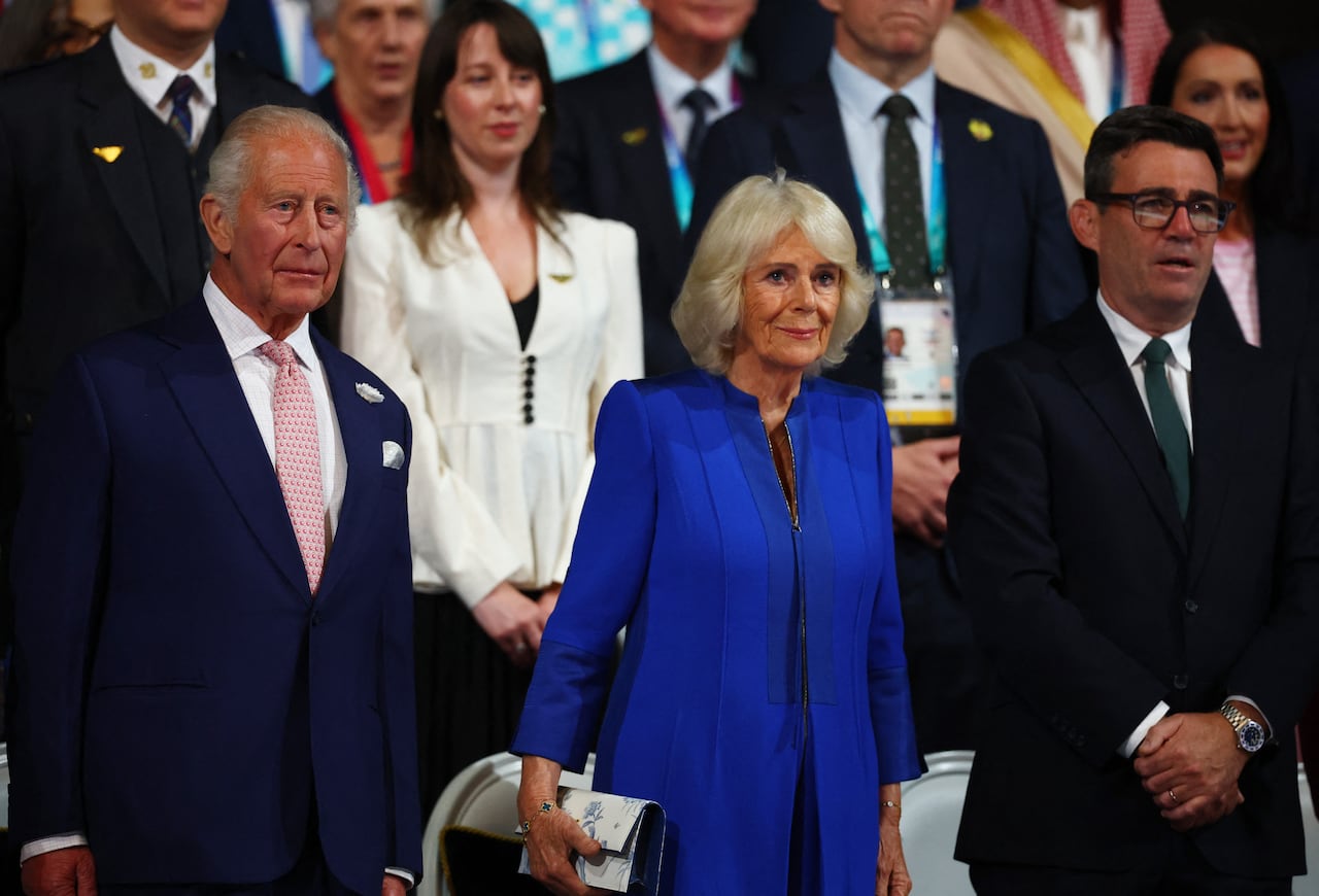 A man and woman in suit and dress stand among a crowd of spectators
