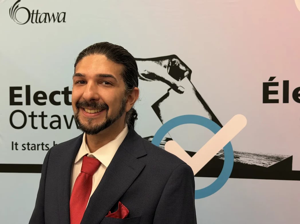A politician in a suit and tie smiles at an election office.