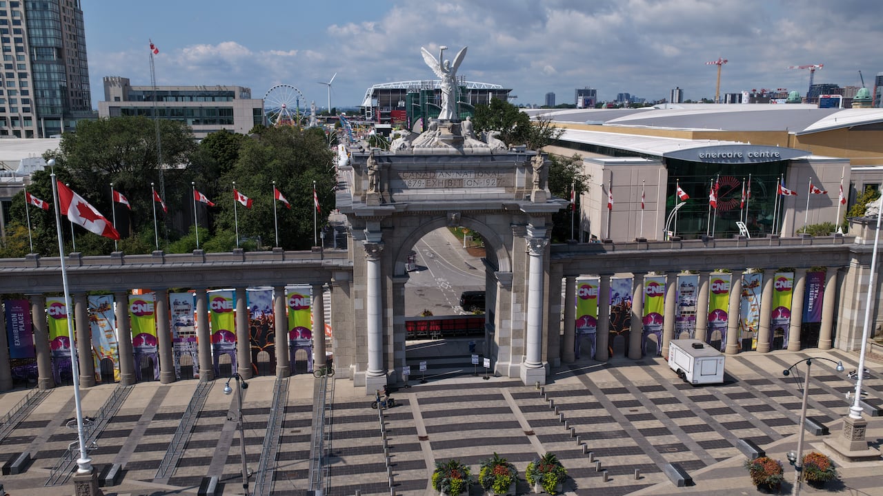 Drone shot of gate with winged statue atop, CNE signage, Ferris wheel visible in the background