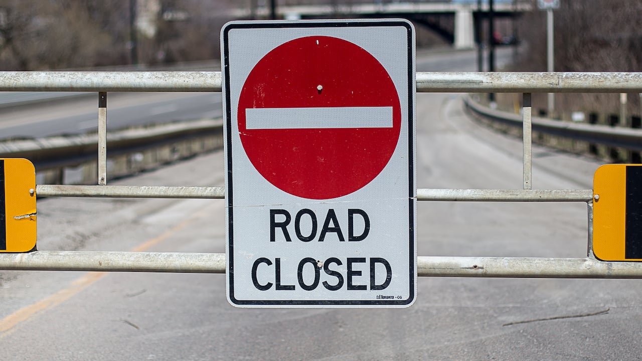 A sign saying "Road Closed" is posted on gate blocking the entrance to a highway.
