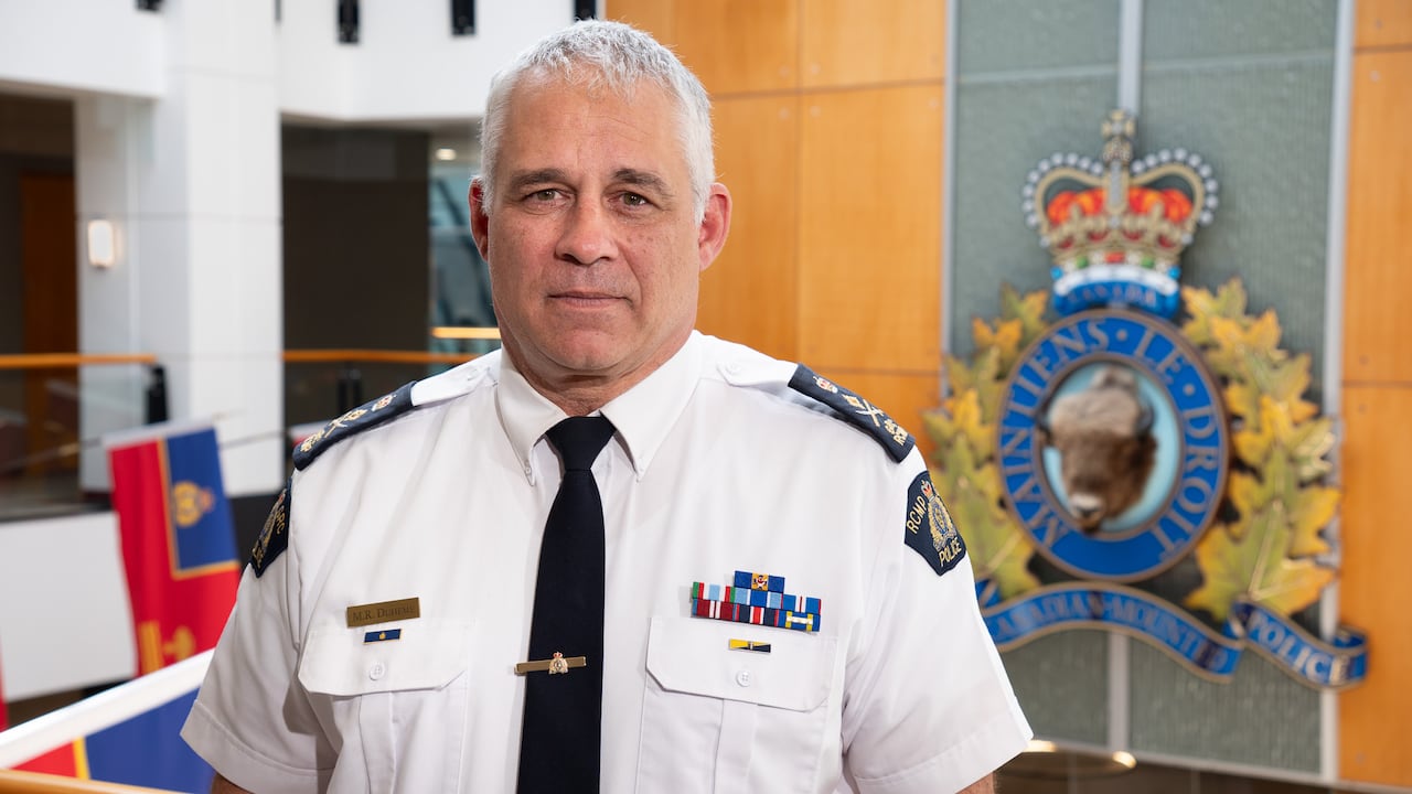 A police officer stands in front of a police emblem.