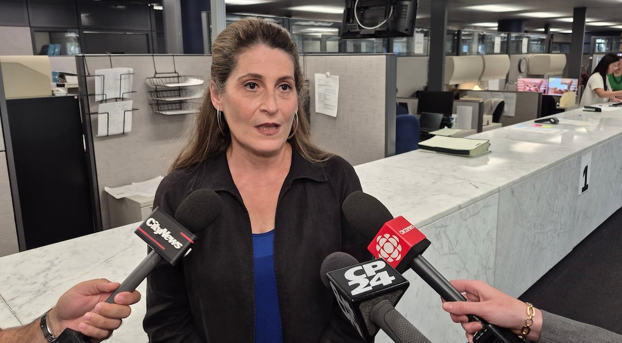 A woman speaks into several mics at an office.