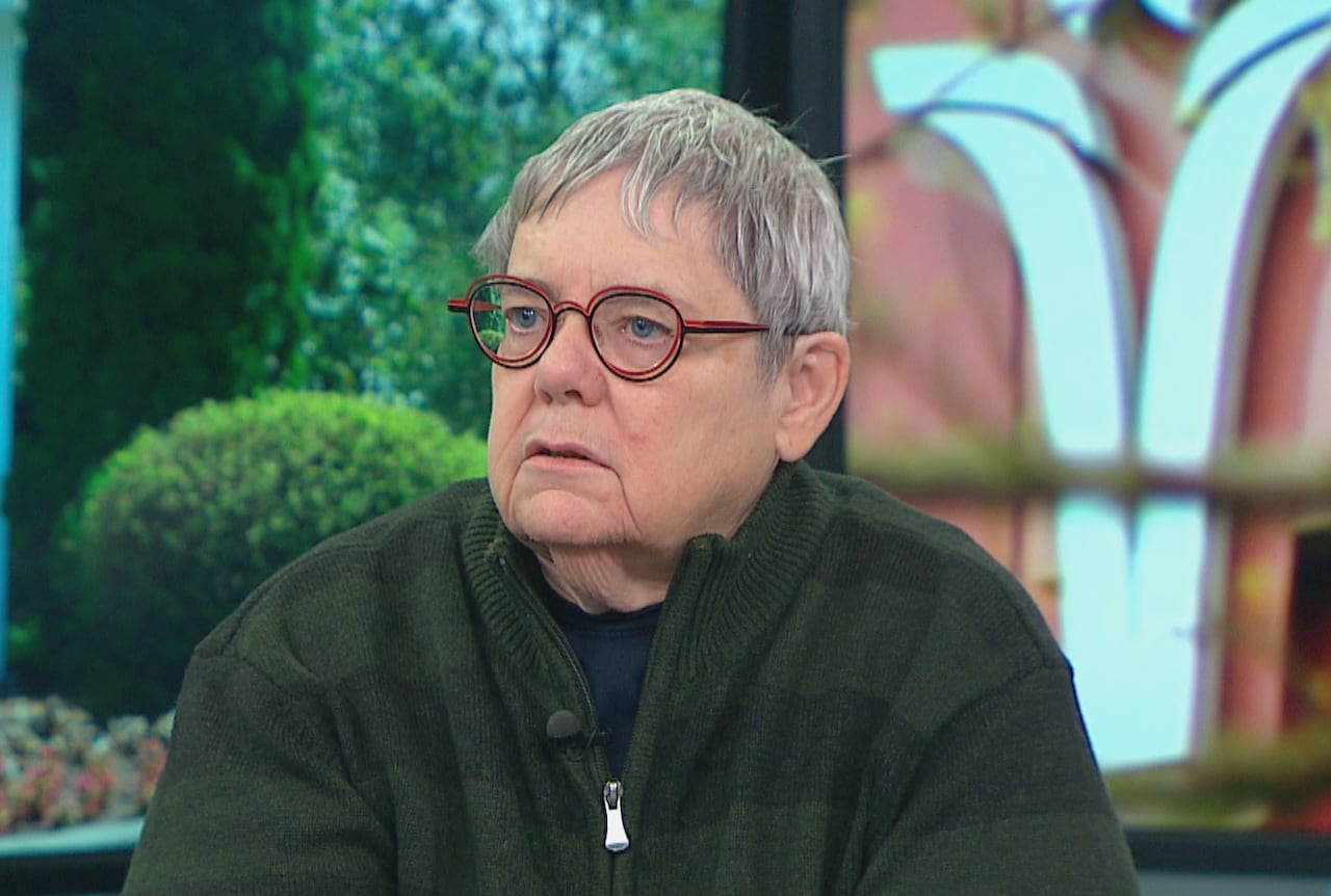 a woman in a green sweater speaks on the news