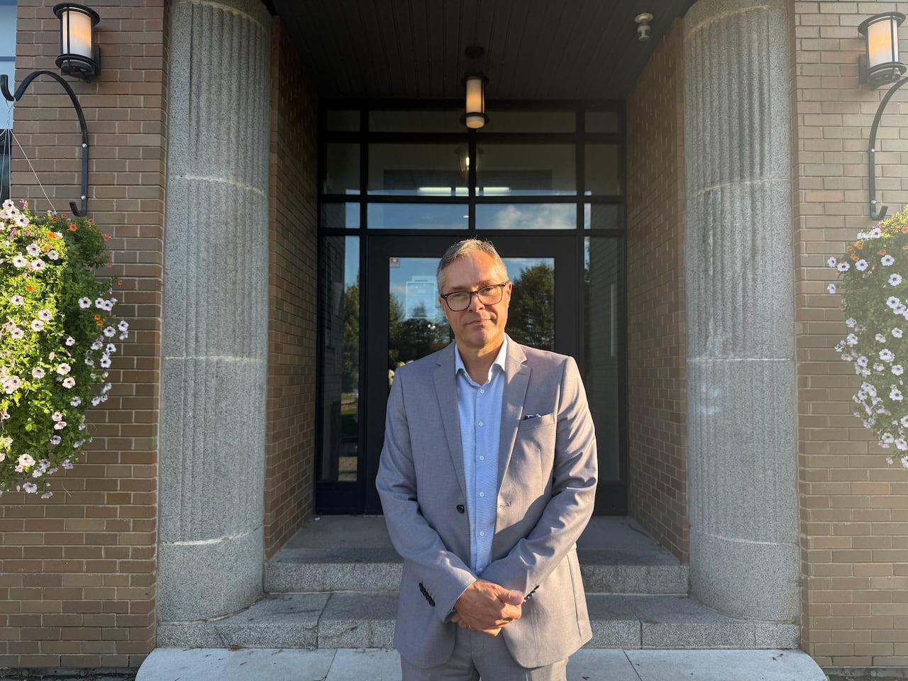 Mayor with glasses stands outside of municipal building