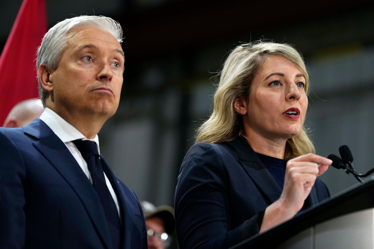 Minister of Industry Melanie Joly speaks as Minister of Finance and National Revenue Francois-Philippe Champagne looks on at a news conference on Canada's response to U.S. tariffs, at a roofing company in Ottawa, on Tuesday, Aug. 25, 2026.