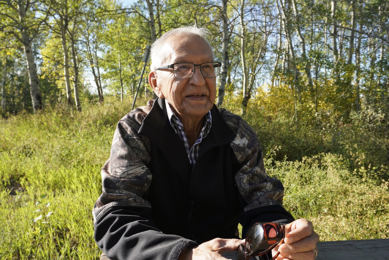 Man sits in front of forest.