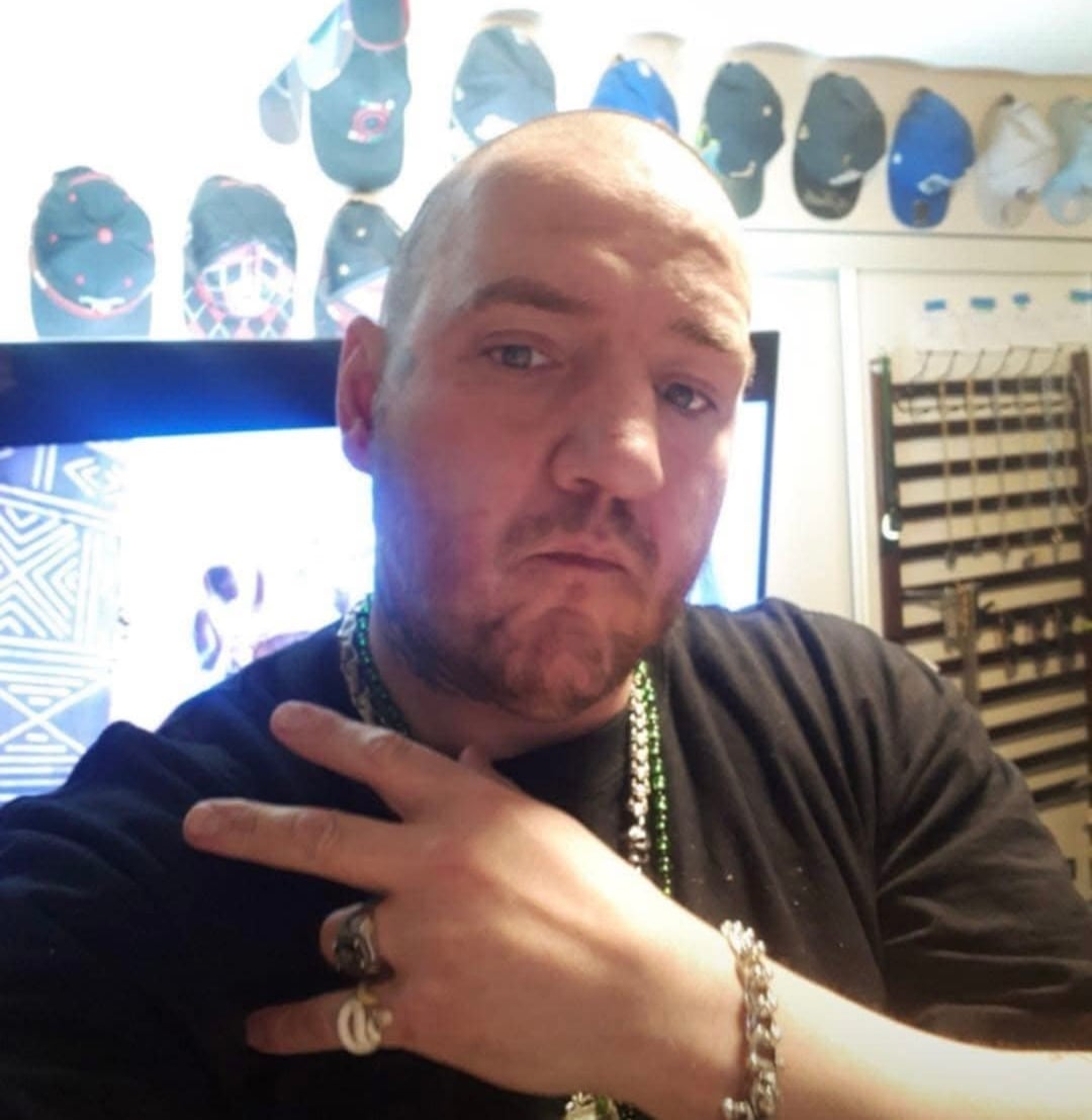 A man strikes a pose with his hand and looks directly at the camera.