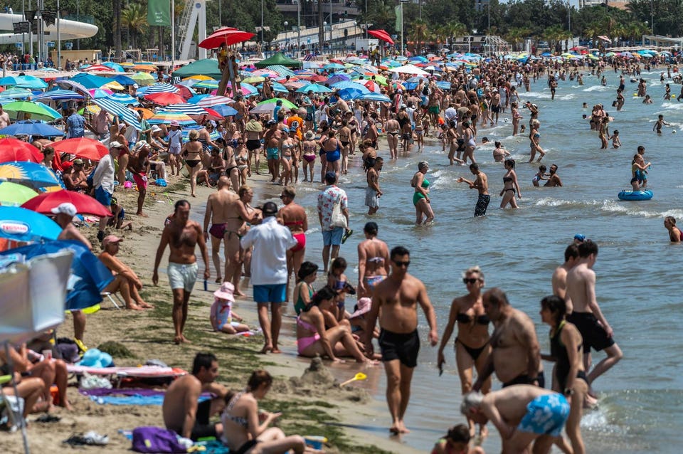 Tourists and locals cool off at a crowded El Postiguet Beach