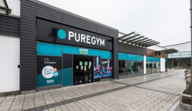 Exterior view of PureGym Aldershot, a modern fitness center with large windows and promotional signage