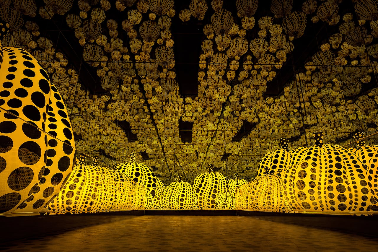 A picture of an art installation of pumpkins covered in black polkadots surrounded by mirrors