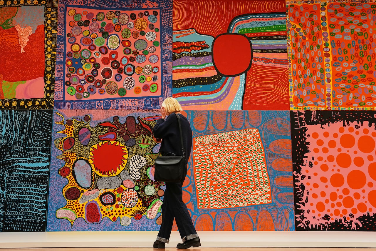 A woman looks at some paintings created by Yayoi Kusama