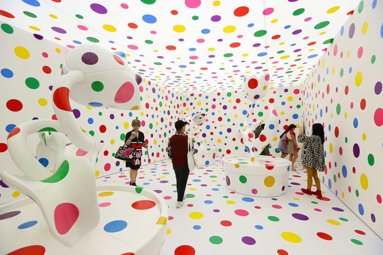 A picture of visitors of a museum standing in a room covered in colourful polkadots