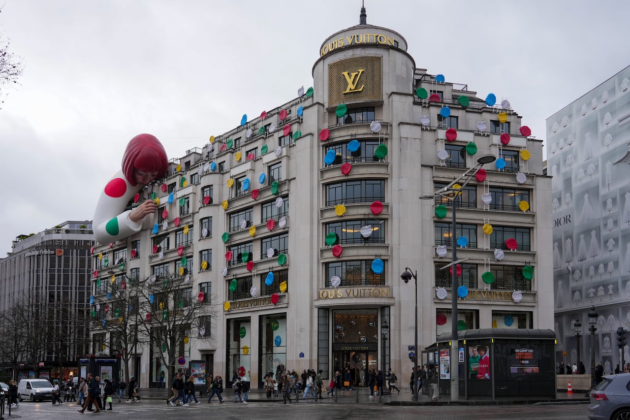 a picture of a yayoi kusama sculpture "paiting" the facade of the Louis Vuitton french headquarters
