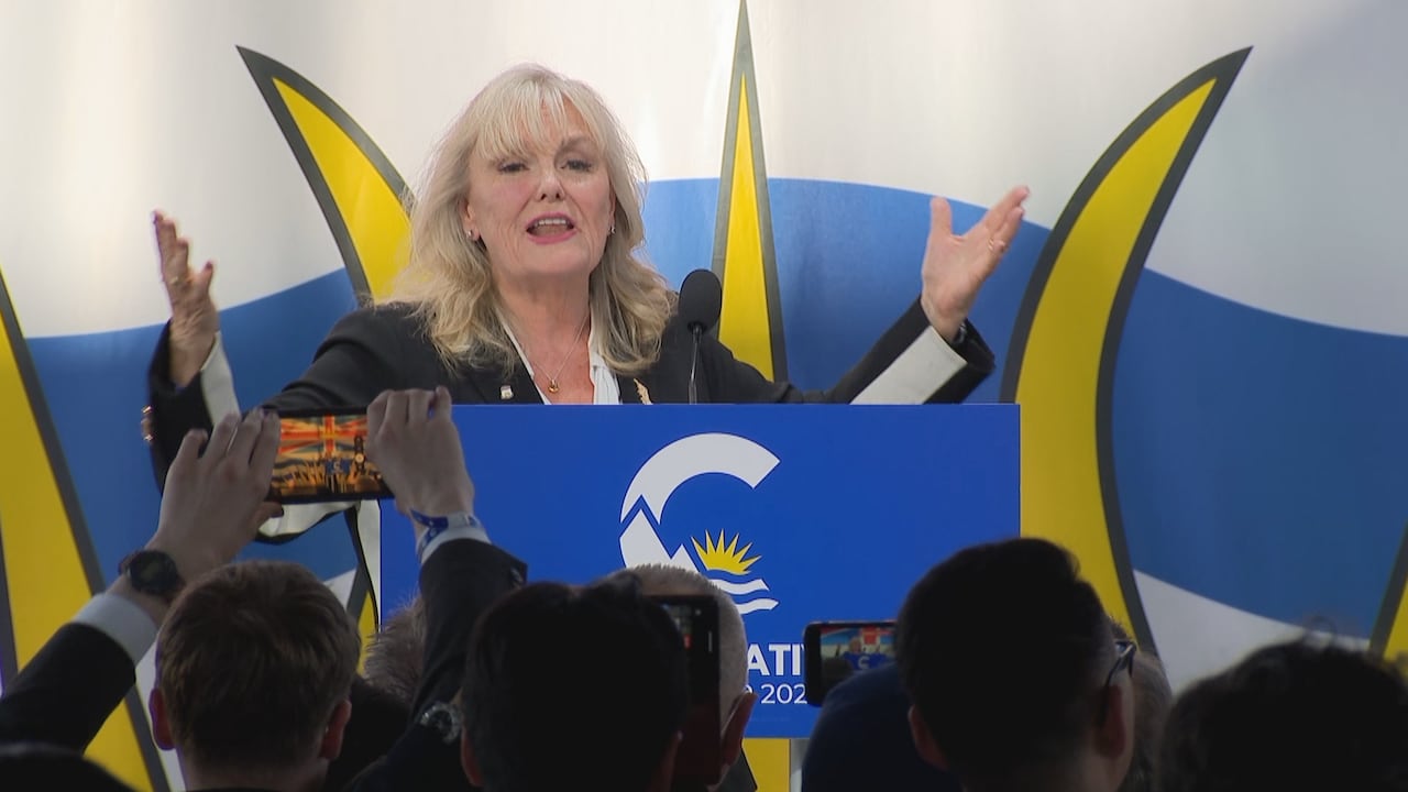 A woman stands at a podium with her hands up.