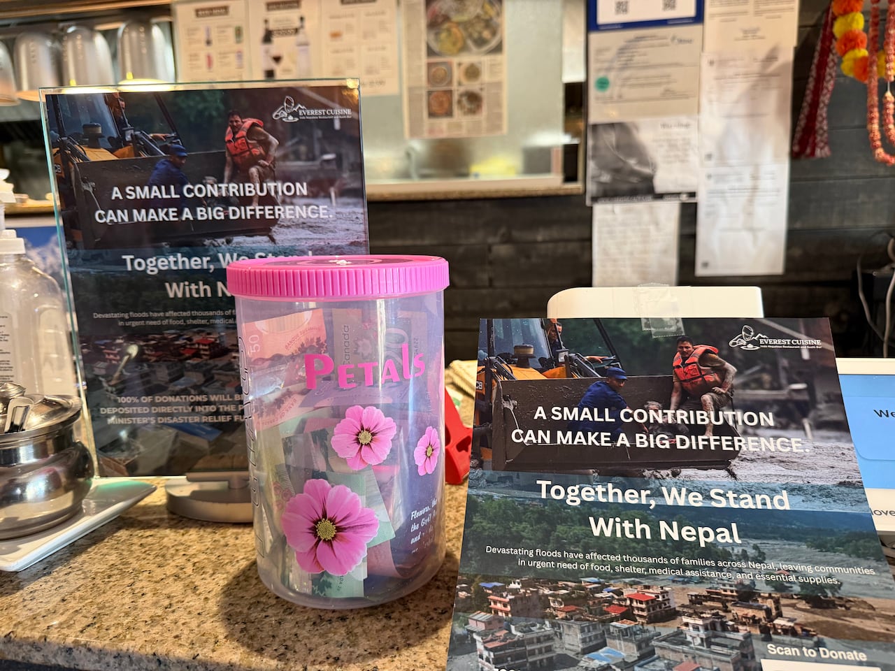 Two posters with pictures of flood damage on them stand next to a jar with money in it.