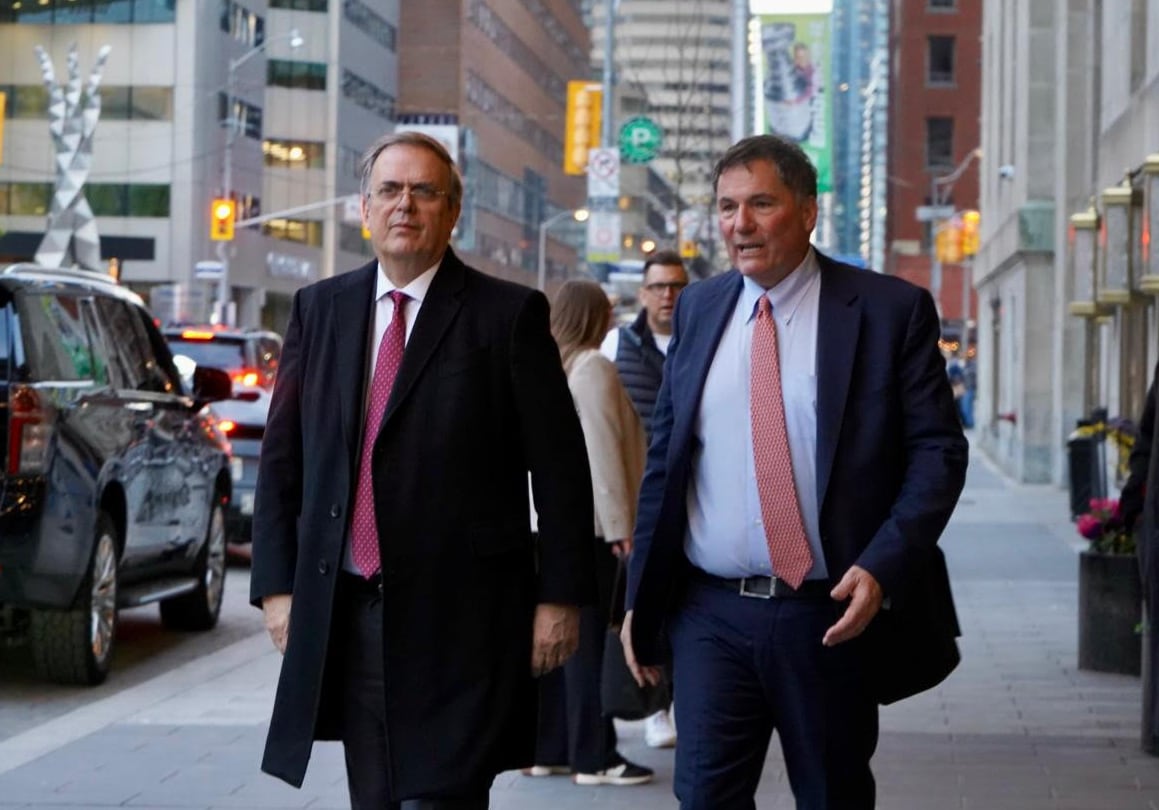 Two men in suits walk along a city street.