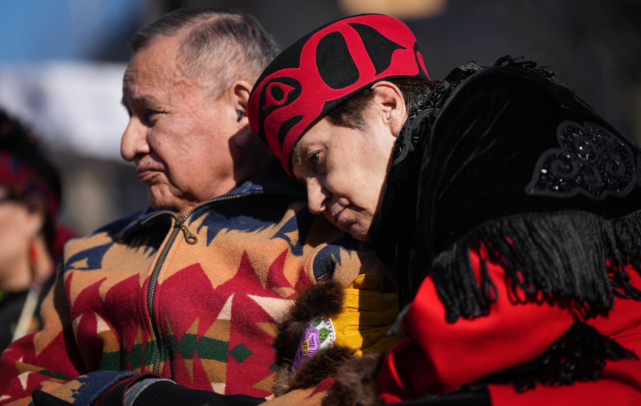 A woman rests her head on a man's shoulder.