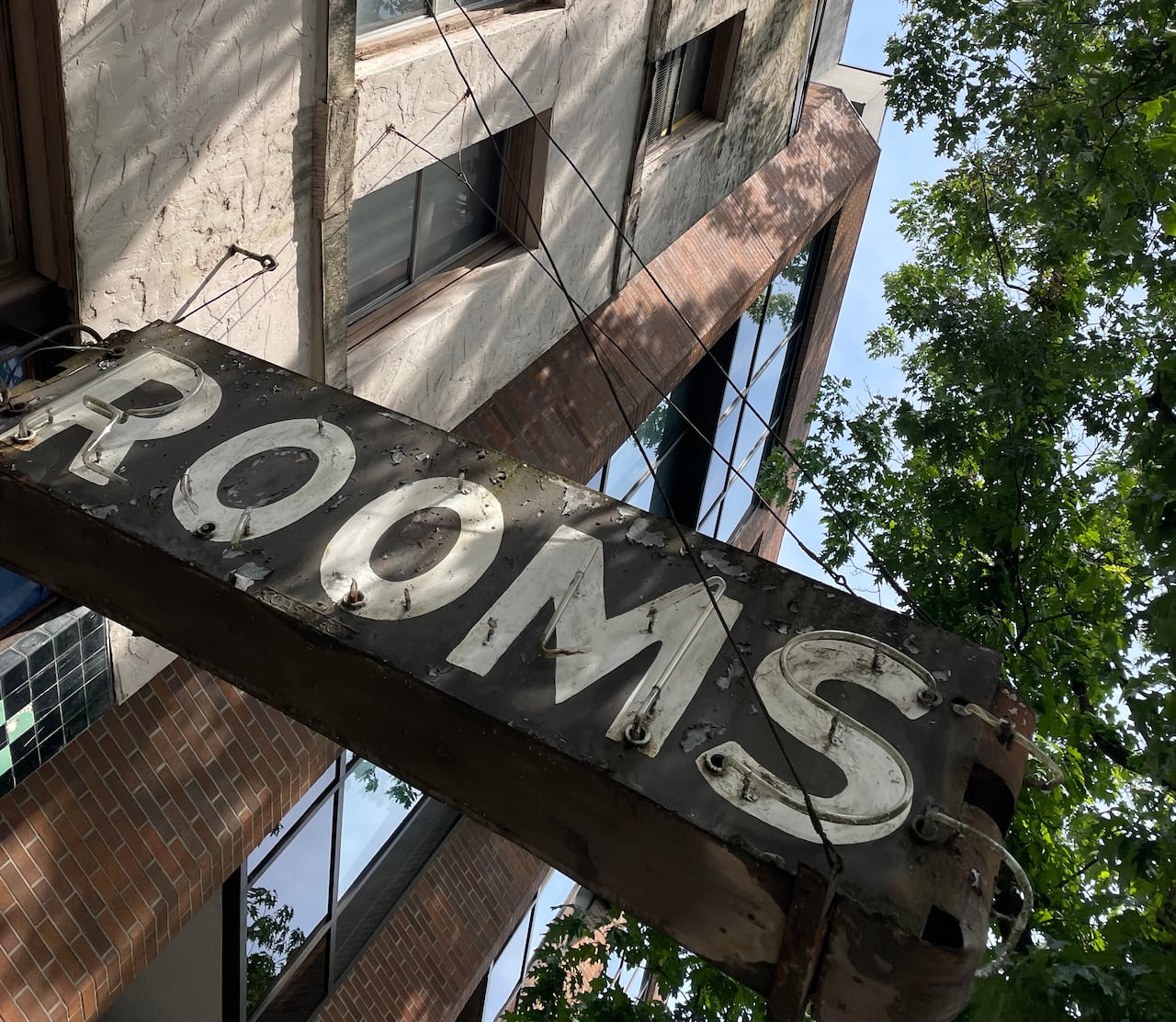 A sign on the front of a building's exterior says "rooms."