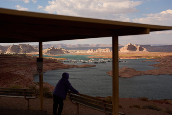 A person stands at an overlook near the Wahweap Marina on Lake Powell at the Glen Canyon National Recreation Area, July 15, 2026, near Page, Ariz. (AP Photo/John Locher, File)