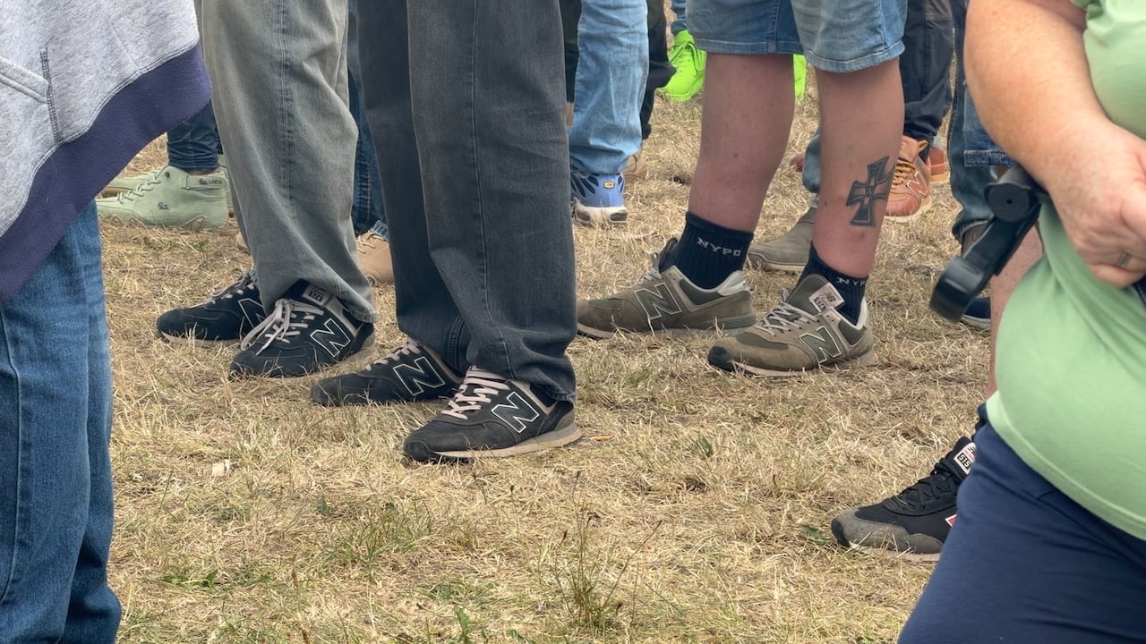 Three pairs of black New Balance sneakers are seen on young men in a crowd at an AfD rally in Germany.