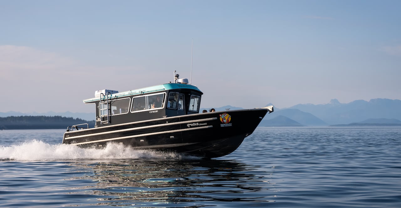 A boat flies across water with mountains in the background.